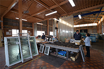 建材総合倉庫は広大な空間。作業スペースで加工課係長の菊池伸司さんの笑顔に迎えられた。ここでは主に住宅向けサッシの加工製作をしているという。「年間50棟分くらいのLow-Eガラス窓を加工しています」