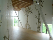 白が基調の１階スペース。若手アーティストに依頼した植物の壁画は、日々描き足され[成長]しているという。(写真提供/曽我部昌史)