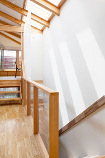 階段の上、片流れ屋根に切られた天窓は、白壁による反射も含めて豊富な自然光を1階まで届ける。