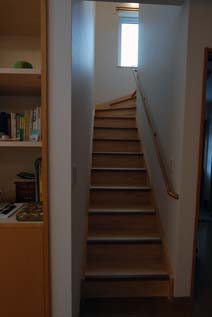 踏面（ふみづら）と段鼻（だんばな）の色を変えて段差を見やすくし、滑り止めに溝を彫り込んだパイン材の階段。これもバリアフリー。