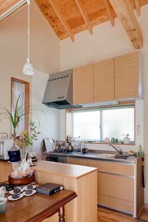 コンパクトで動きやすい小ぶりのキッチンは、正面に引き違い、脇にジャロジーと２つの窓に囲まれ明るい。エコガラスのジャロジー窓は北側の共有玄関外部に向き「夏はここを開けると涼しいんですよ」